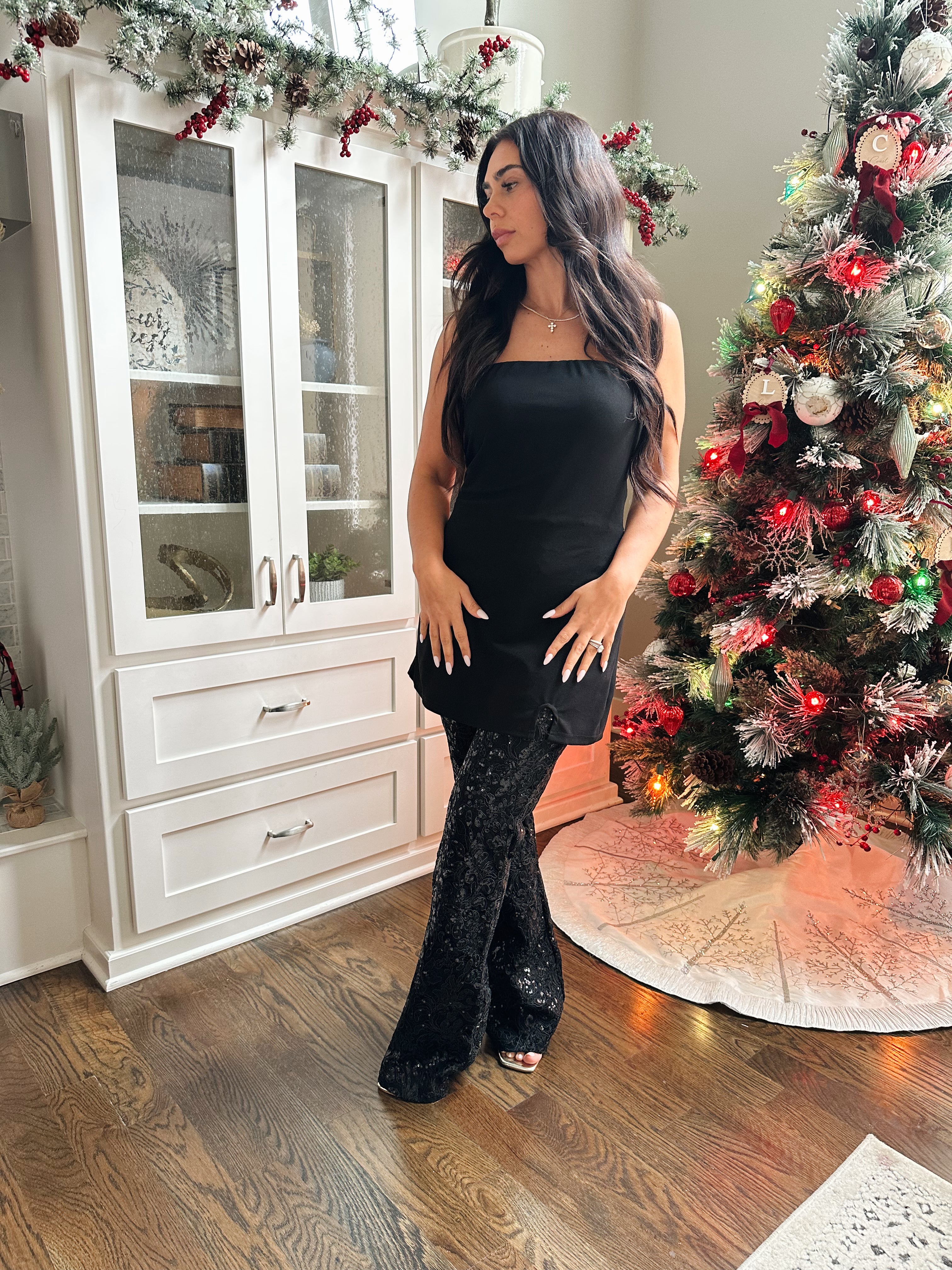 Woman wearing strapless black sequin jumpsuit.