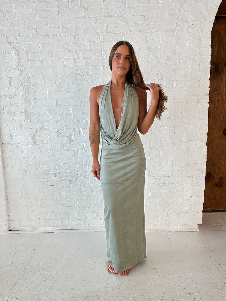 Woman wearing sage green faux suede two piece set with halter plunging cowl top, and maxi skirt. 