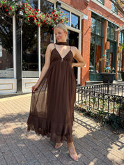 Woman wearing brown maxi dress with beaded detailing and detachable neck scarf.