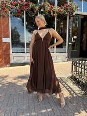 Woman wearing brown maxi dress with beaded detailing and detachable neck scarf.