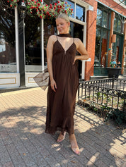 Woman wearing brown maxi dress with beaded detailing and detachable neck scarf.