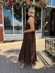 Woman wearing brown maxi dress with beaded detailing and detachable neck scarf.