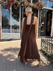 Woman wearing brown maxi dress with beaded detailing and detachable neck scarf.