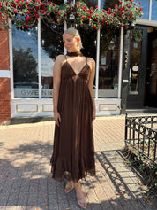 Woman wearing brown maxi dress with beaded detailing and detachable neck scarf.