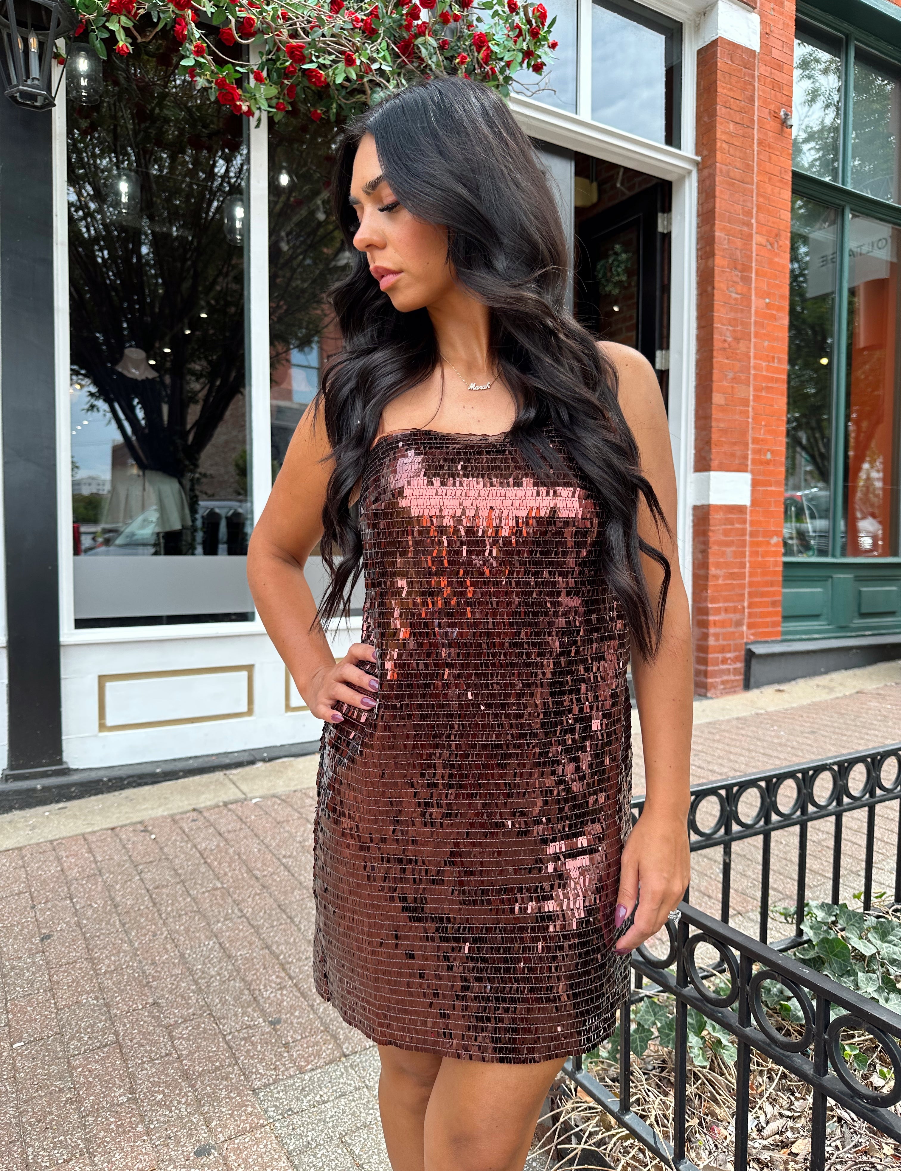 Woman wearing brown sequin shift mini dress with straight neckline and adjustable straps. 
