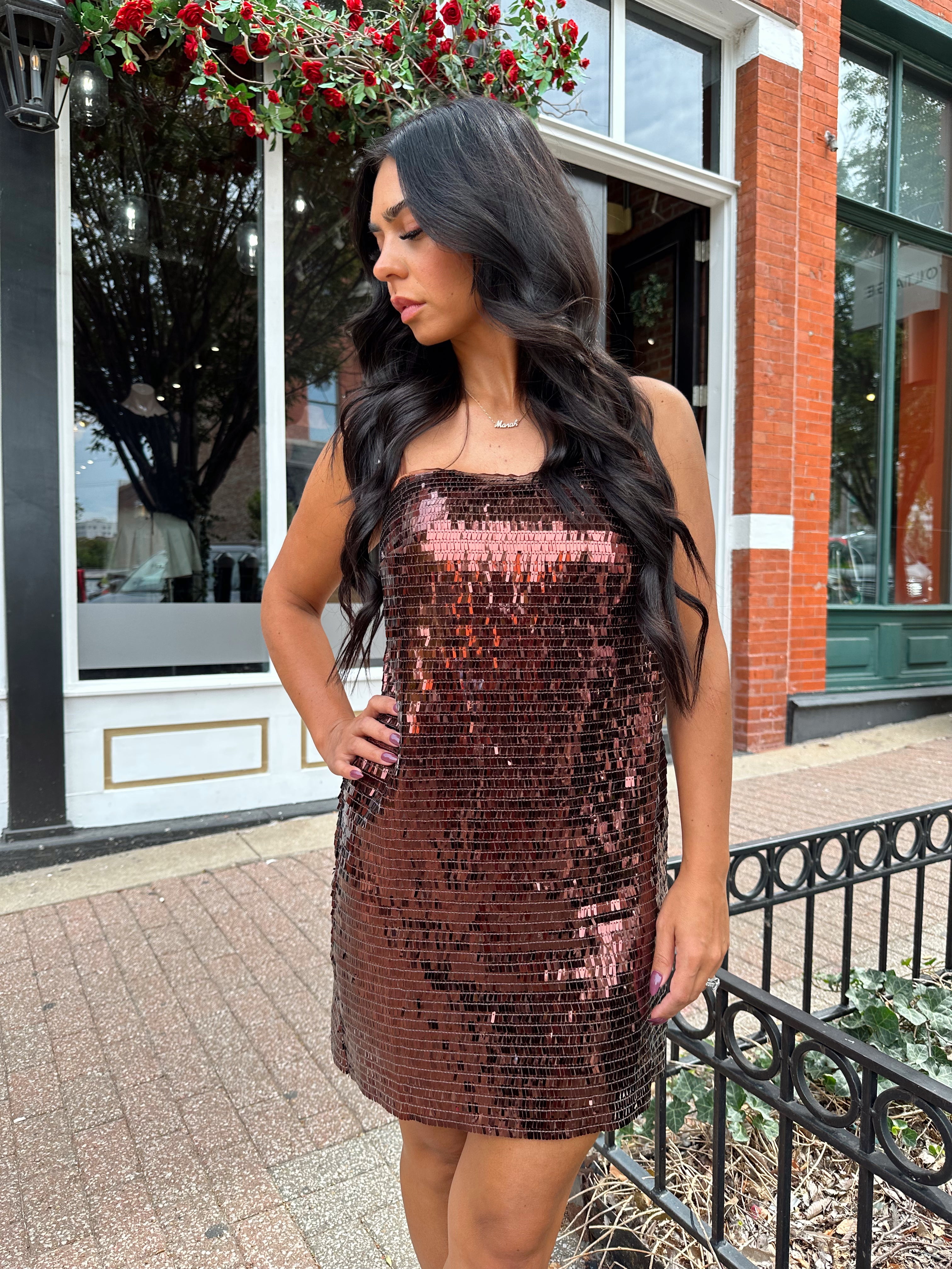 Woman wearing brown sequin shift mini dress with straight neckline and adjustable straps. 