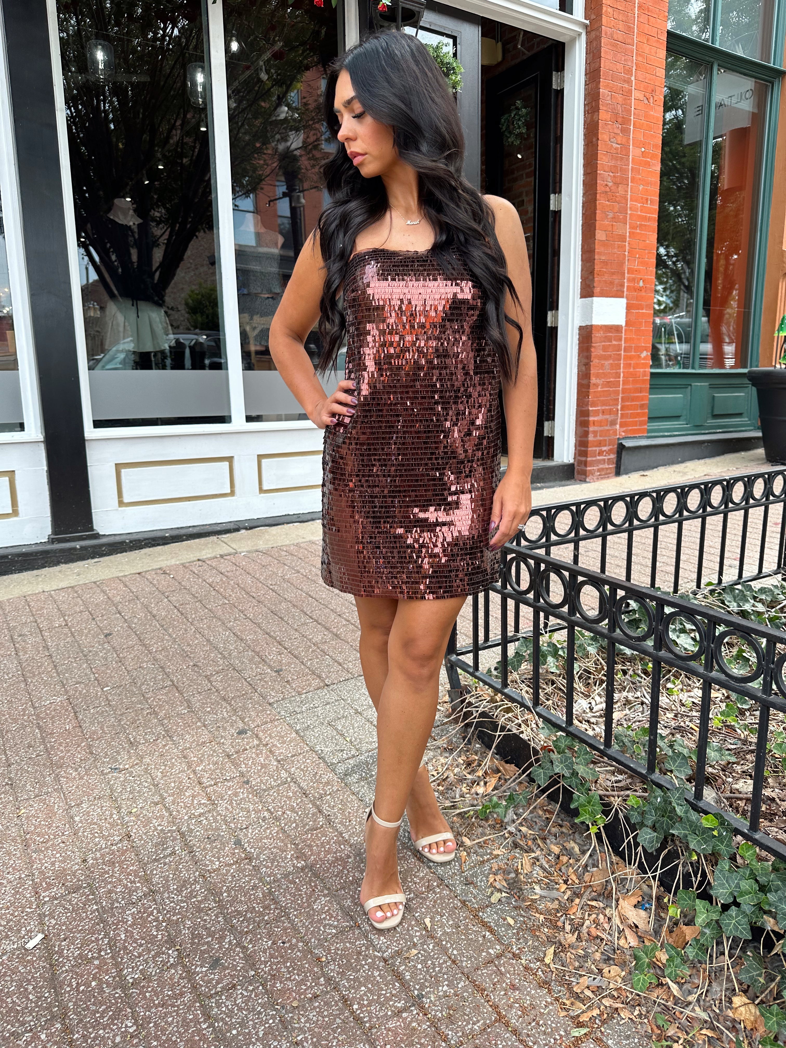 Woman wearing brown sequin shift mini dress with straight neckline and adjustable straps. 