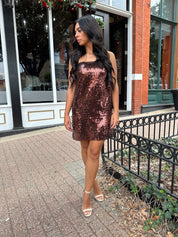 Woman wearing brown sequin shift mini dress with straight neckline and adjustable straps. 