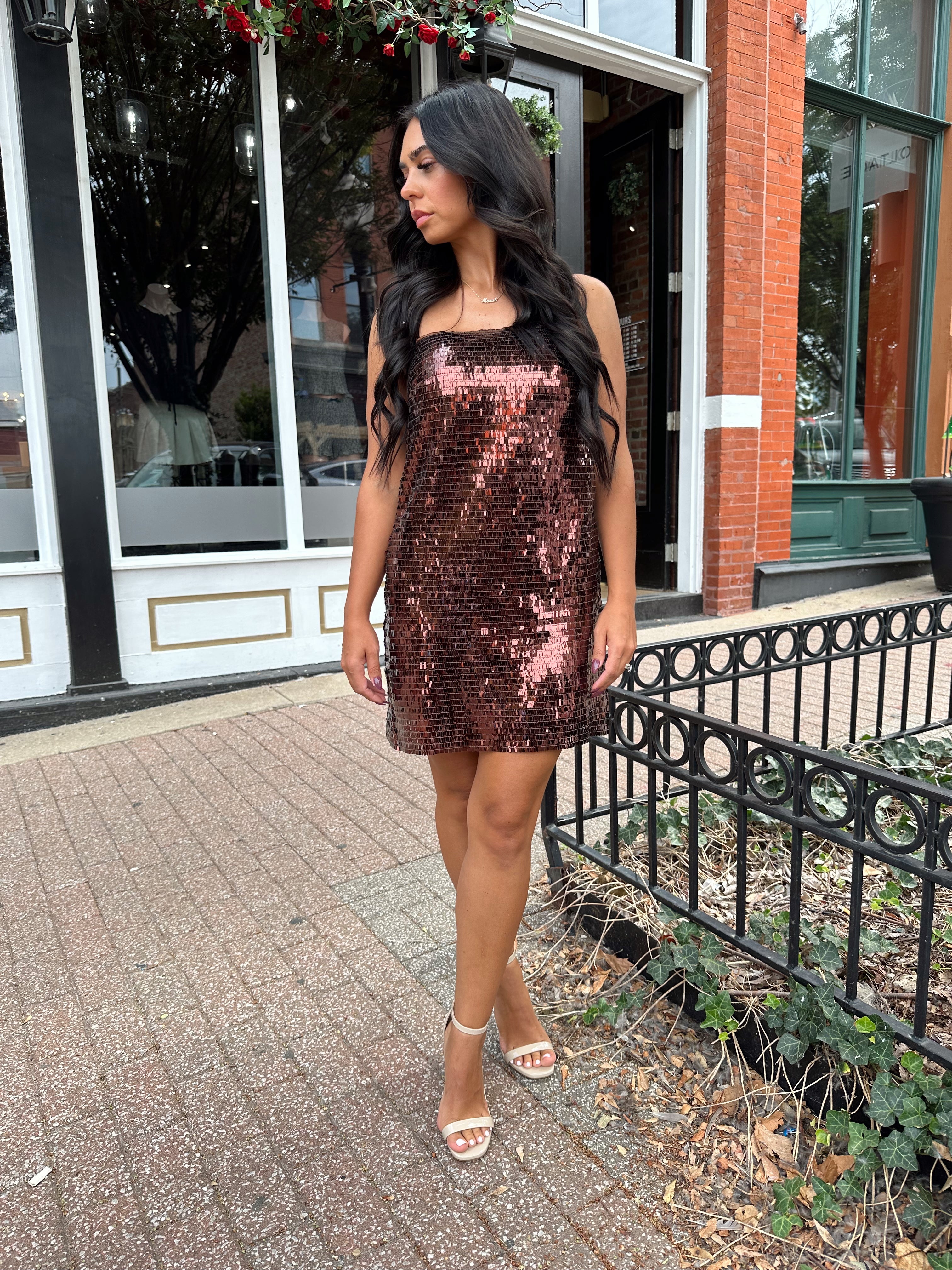 Woman wearing brown sequin shift mini dress with straight neckline and adjustable straps. 
