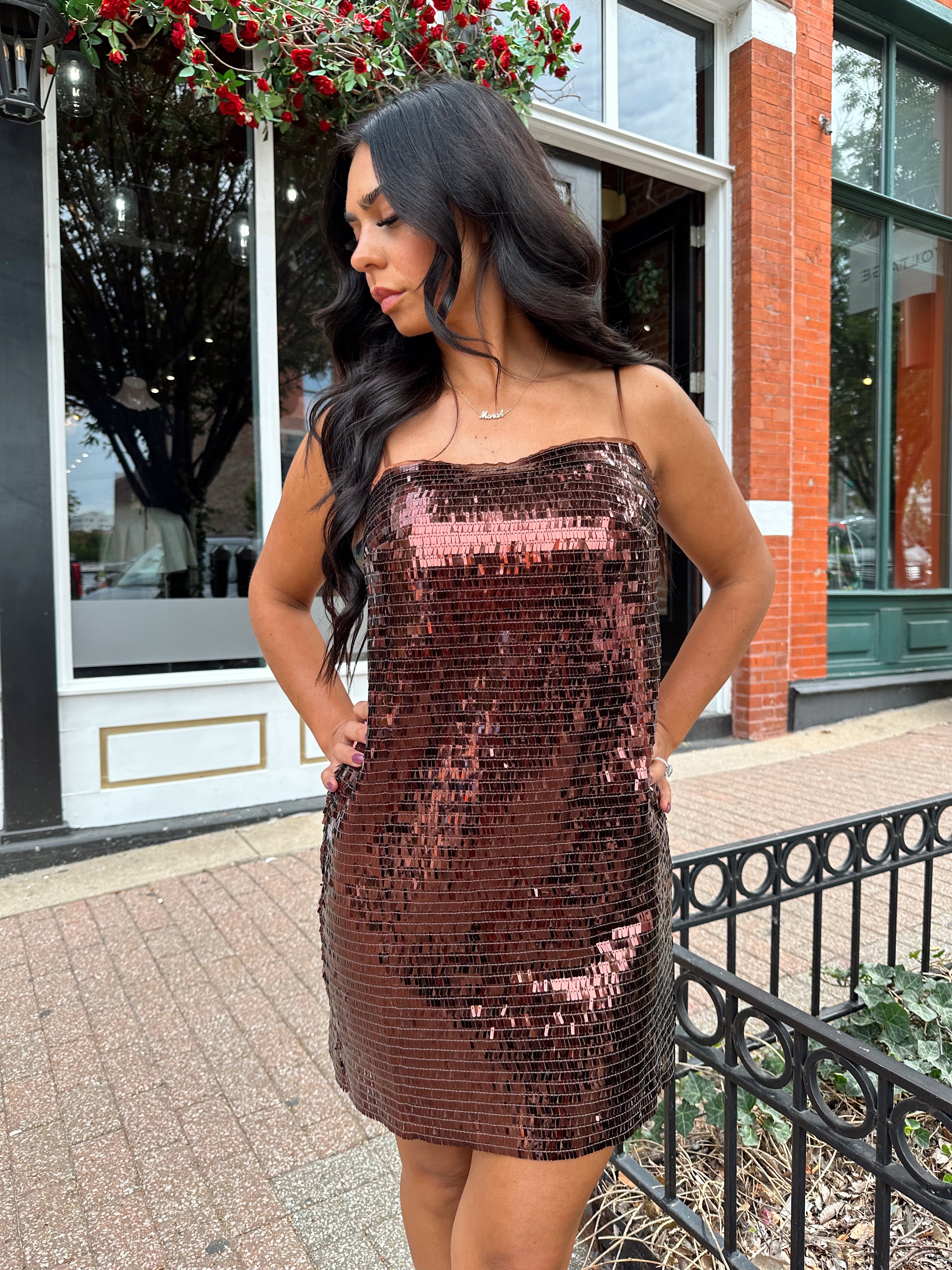 Woman wearing brown sequin shift mini dress with straight neckline and adjustable straps. 