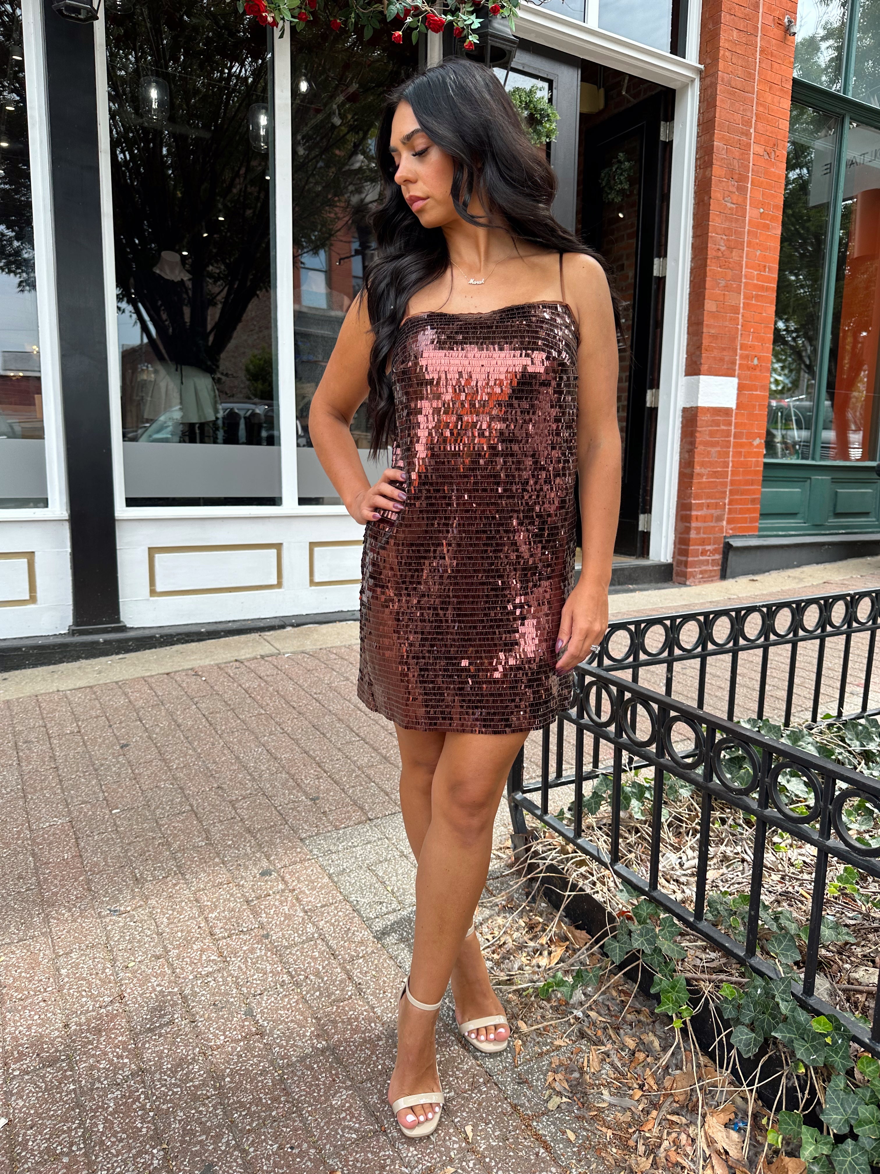 Woman wearing brown sequin shift mini dress with straight neckline and adjustable straps. 