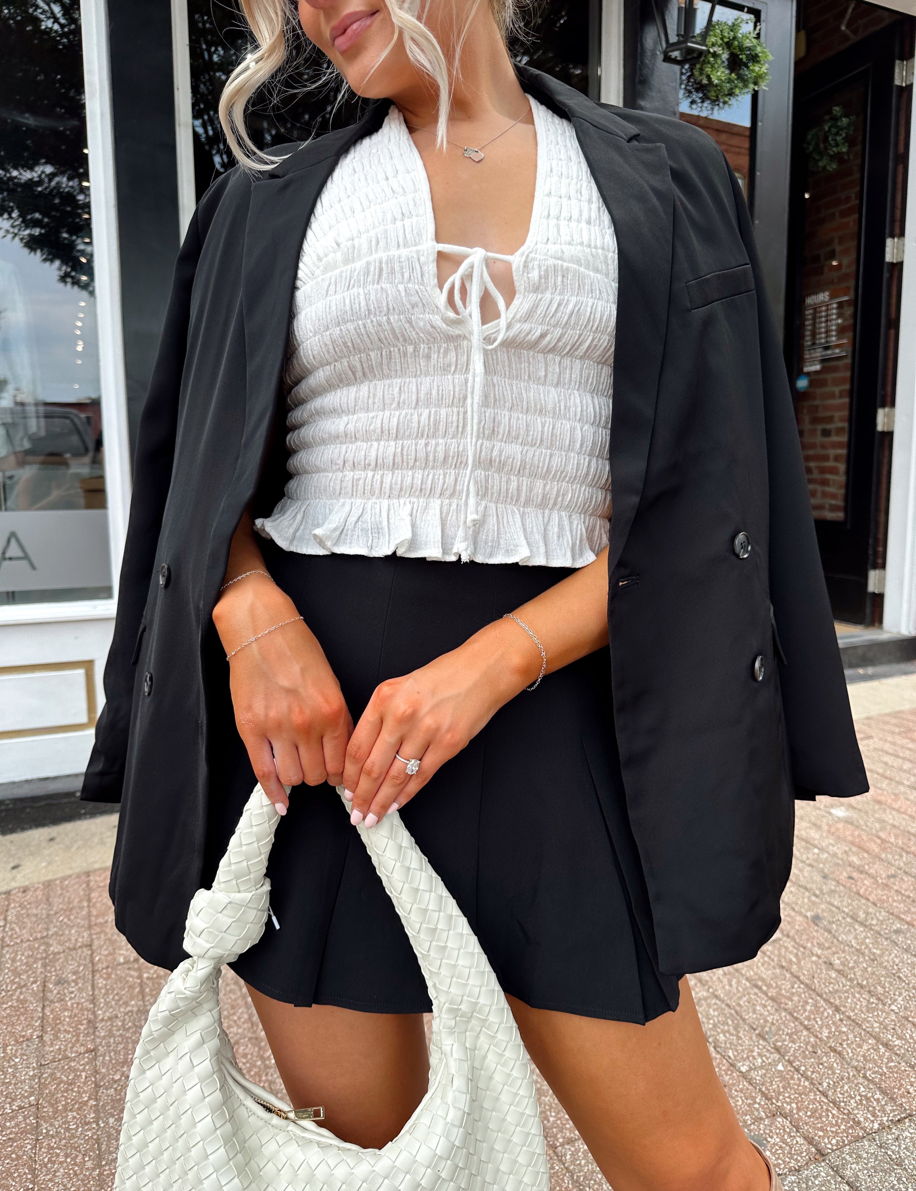 Woman wearing black tailored oversize blazer with collar and button closure. 