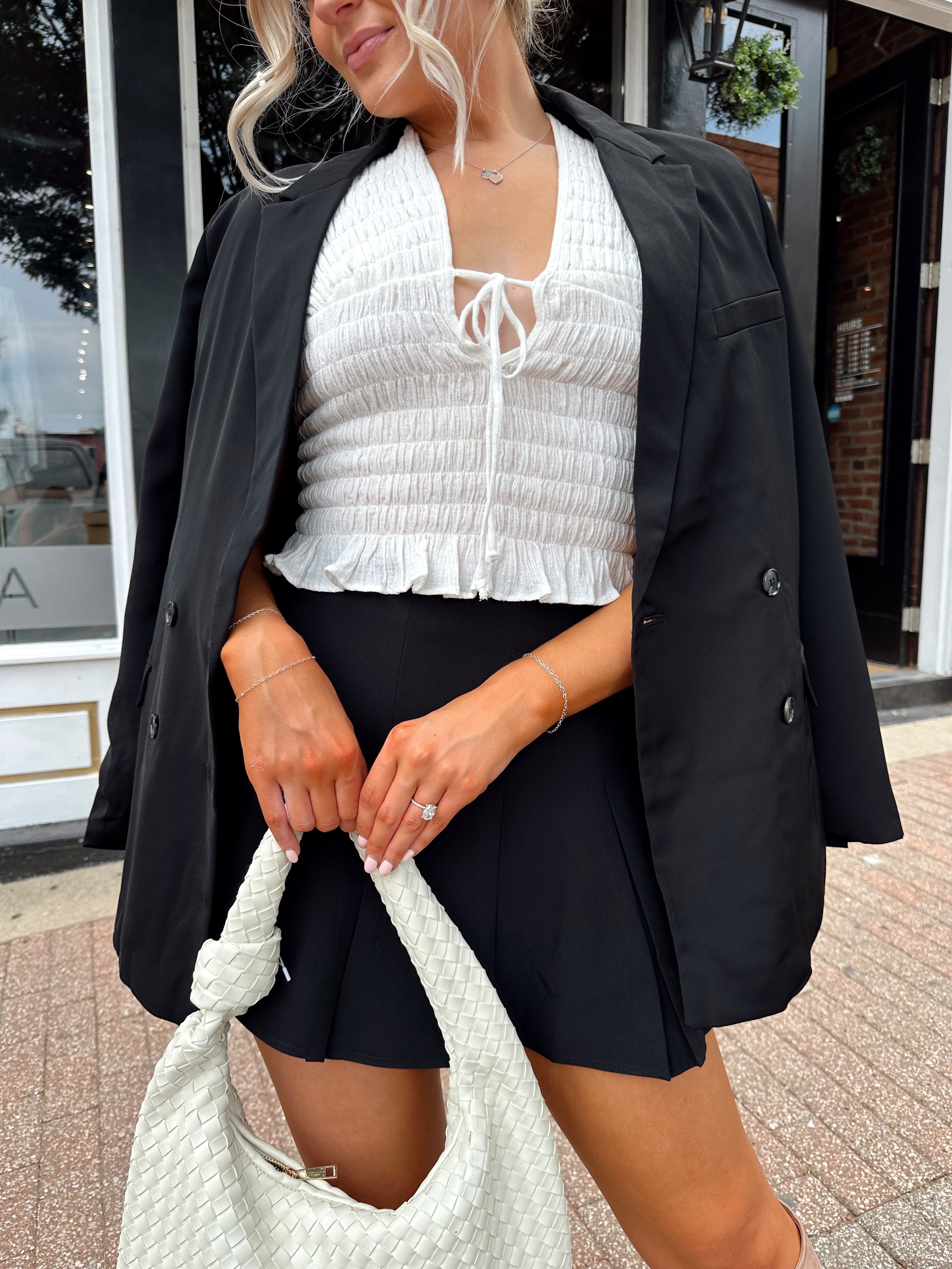 Woman wearing black tailored oversize blazer with collar and button closure. 