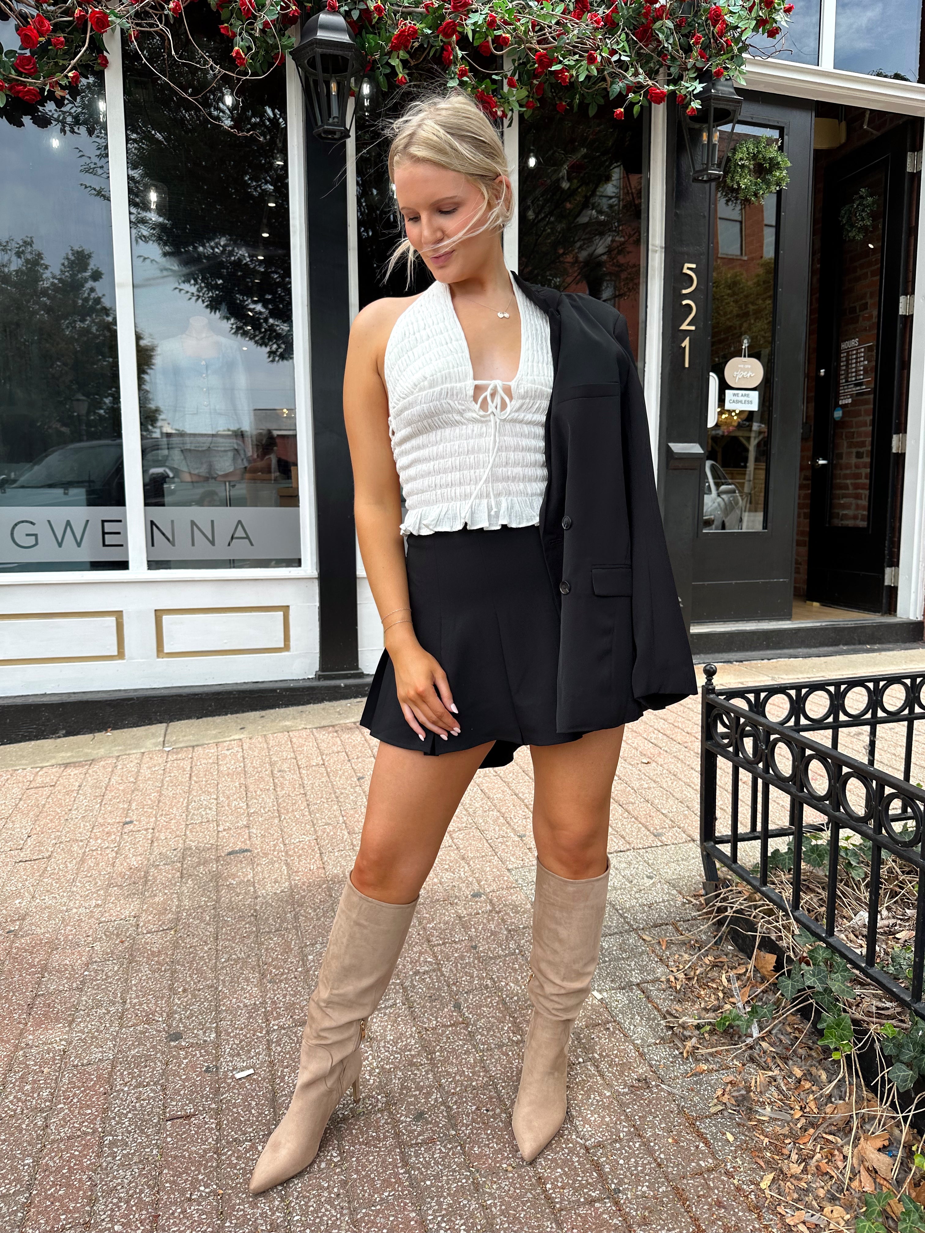 Woman wearing black tailored oversize blazer with collar and button closure. 