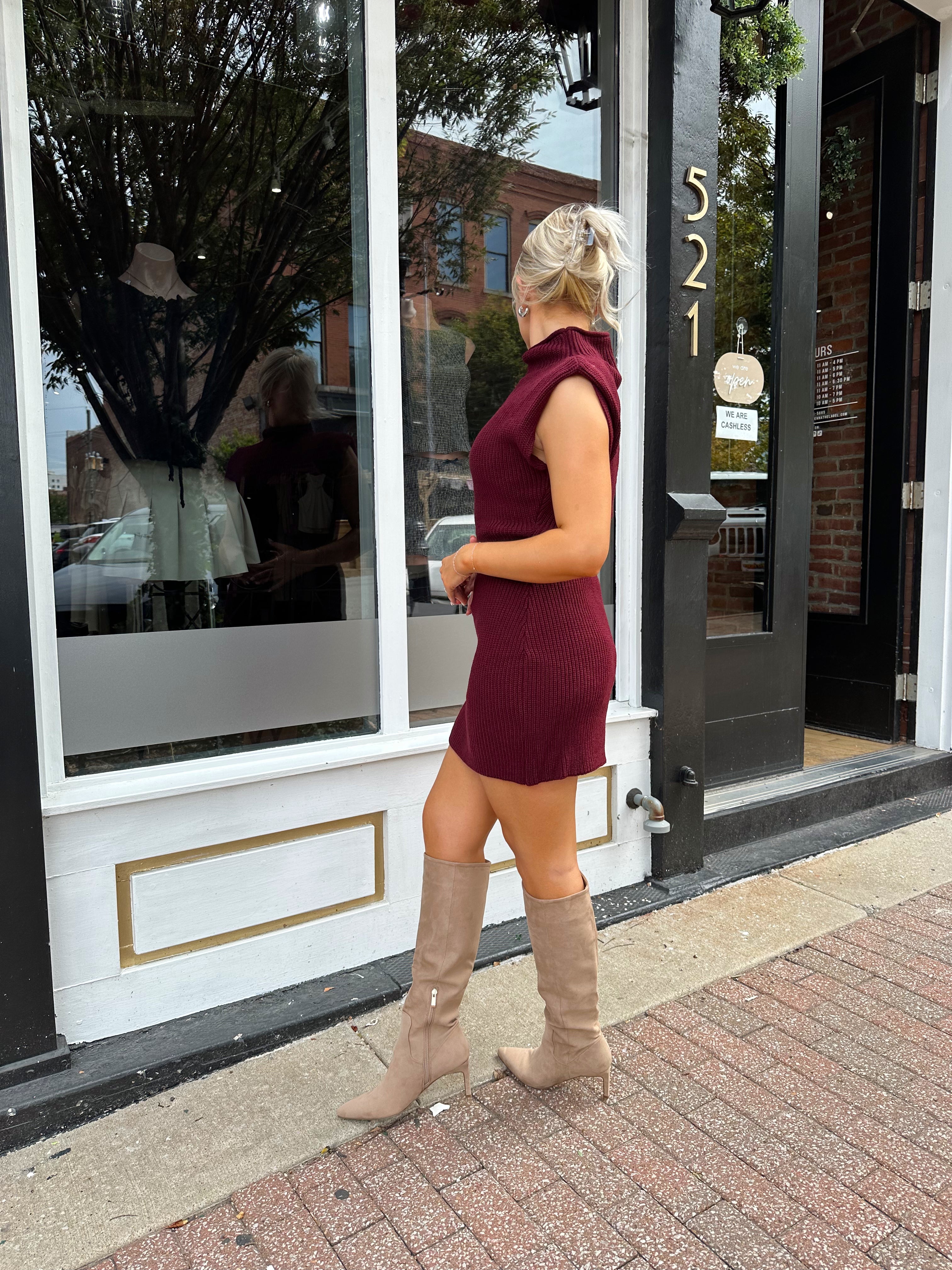 Woman wearing burgundy ribbed sweater mini dress with belted waist and mock neck.