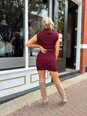 Woman wearing burgundy ribbed sweater mini dress with belted waist and mock neck.