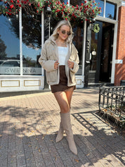 Woman wearing oversized taupe sherpa lined leather jacket.