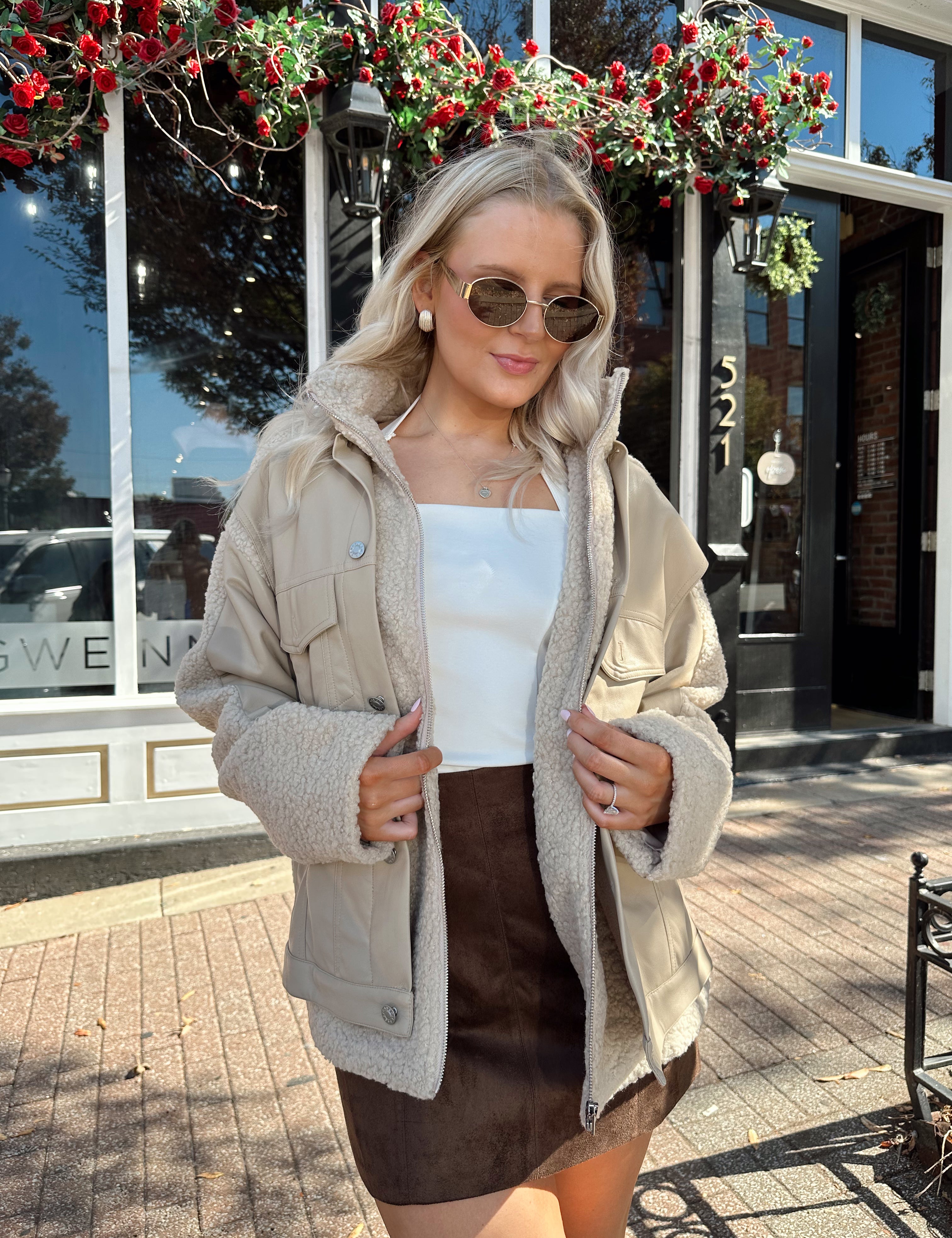 Woman wearing oversized taupe sherpa lined leather jacket.