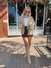 Woman wearing oversized taupe sherpa lined leather jacket.