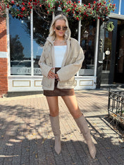 Woman wearing oversized taupe sherpa lined leather jacket.