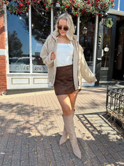Woman wearing oversized taupe sherpa lined leather jacket.