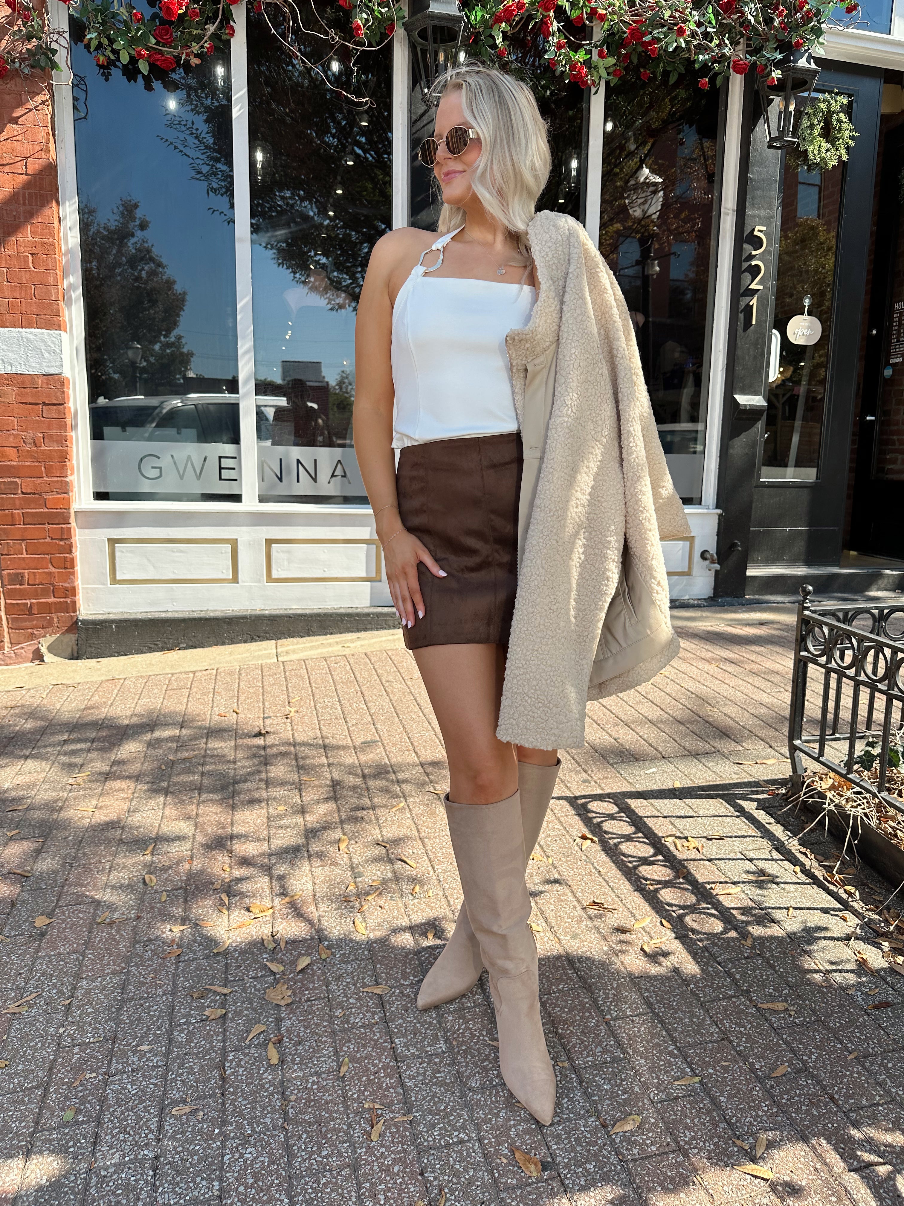 Woman wearing oversized taupe sherpa lined leather jacket.