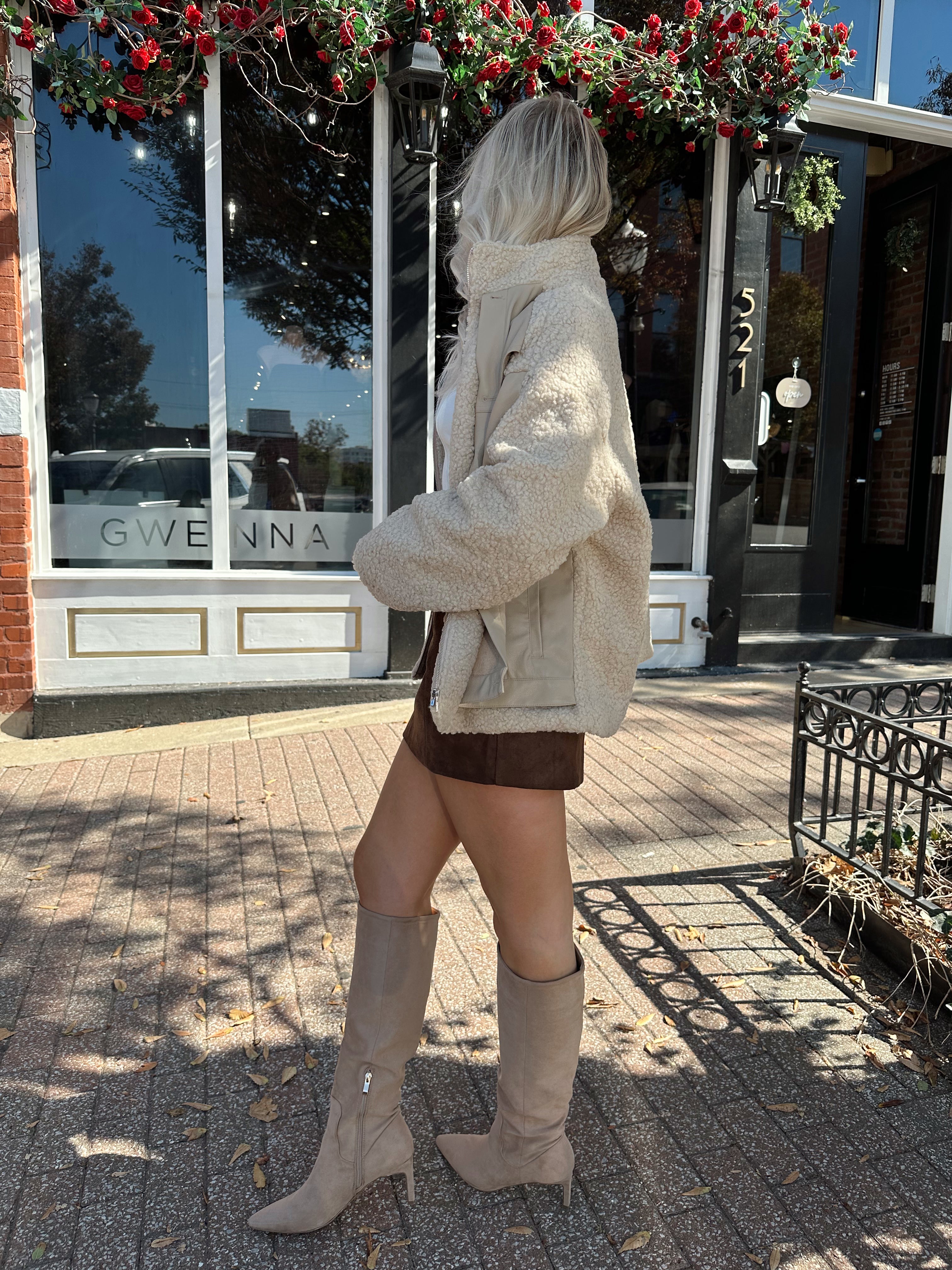 Woman wearing oversized taupe sherpa lined leather jacket.