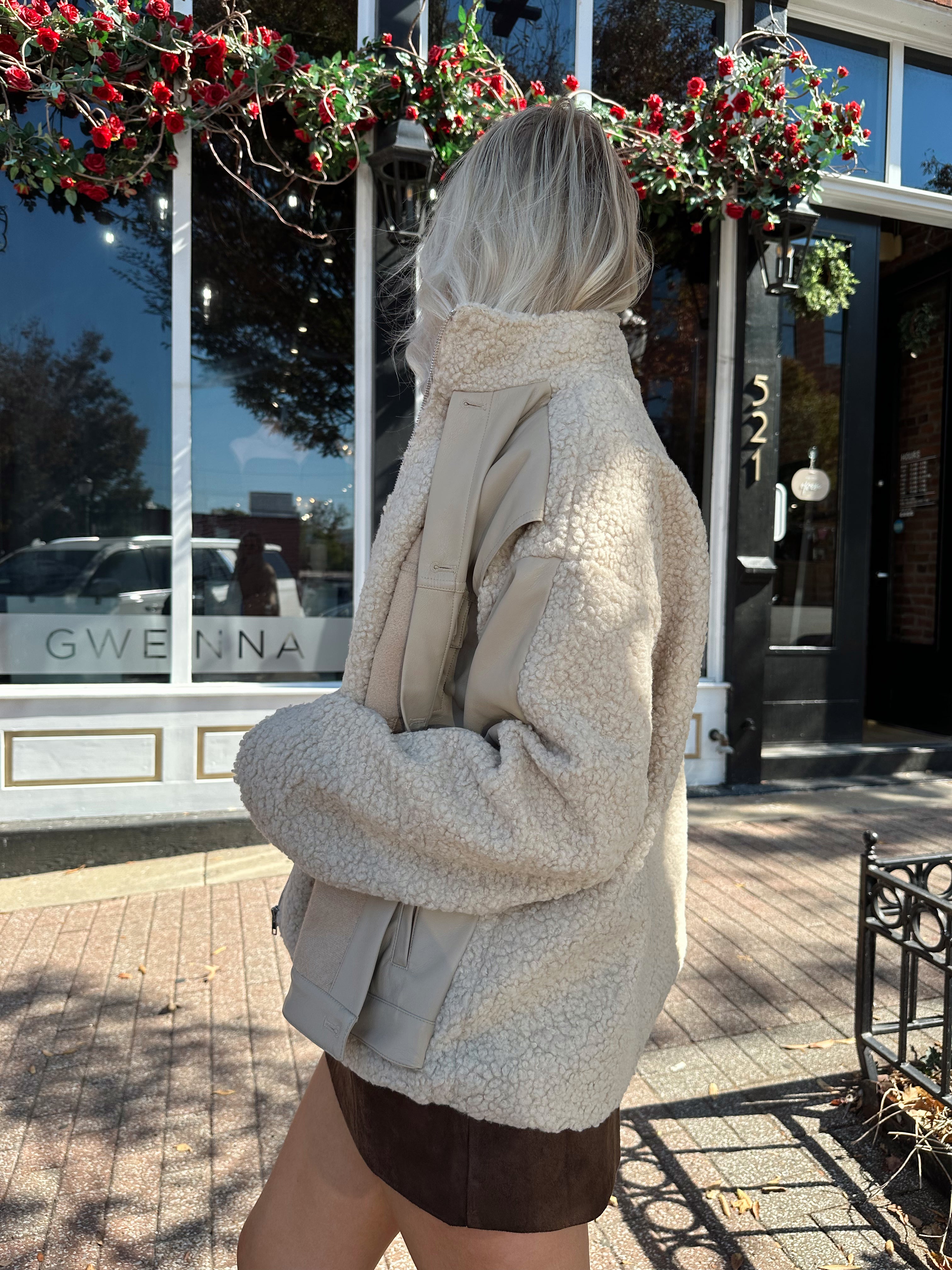 Woman wearing oversized taupe sherpa lined leather jacket.