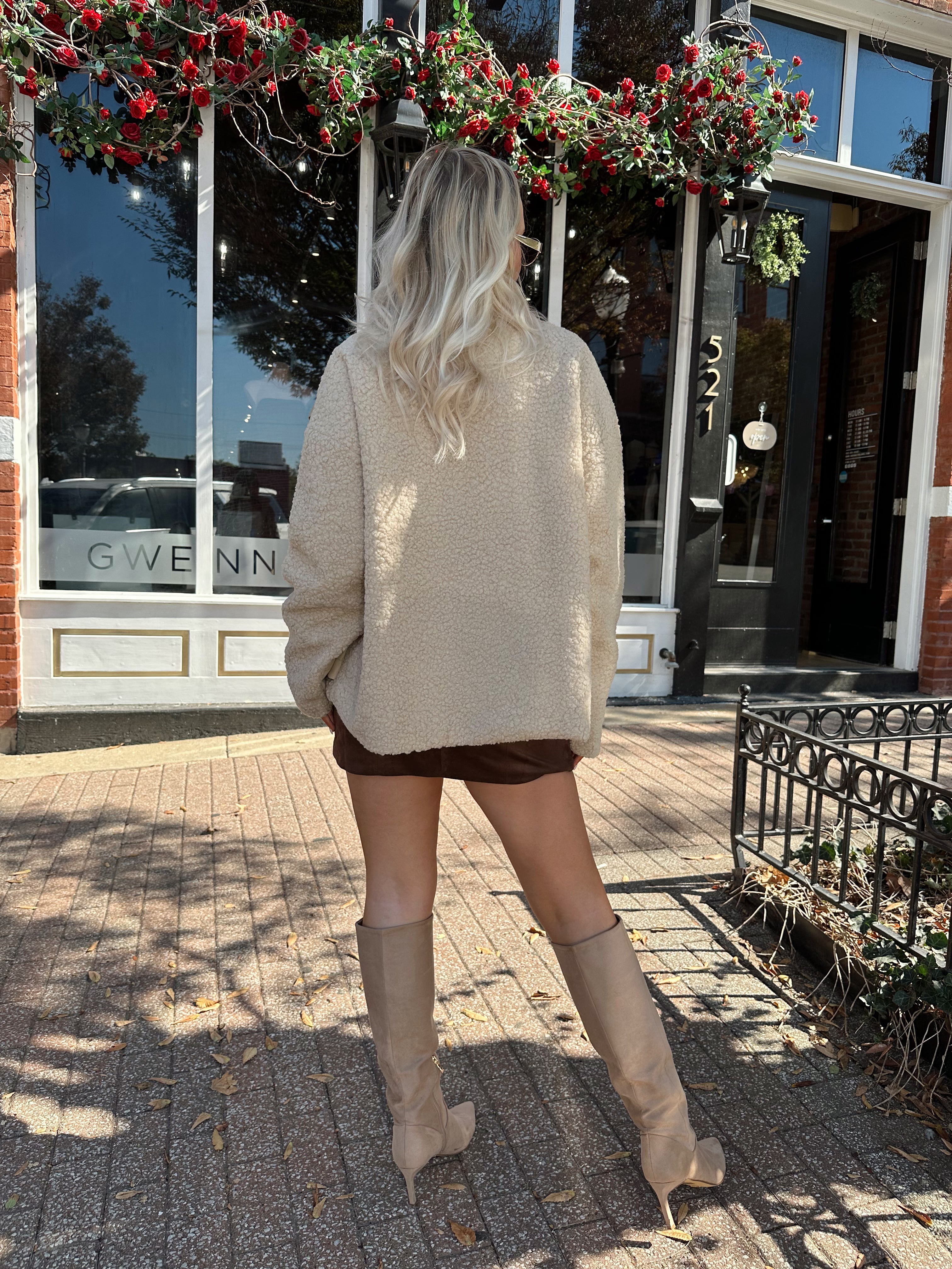 Woman wearing oversized taupe sherpa lined leather jacket.