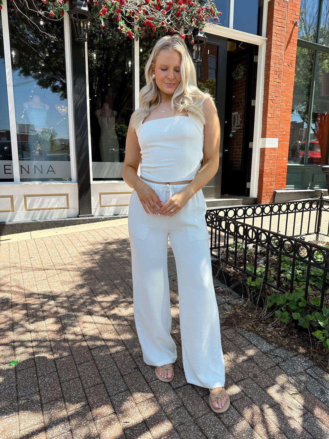 Woman wearing cream two piece pant set with square neck halter top. 