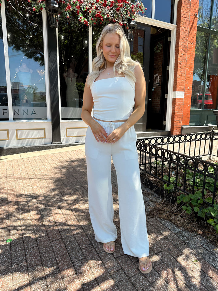 Woman wearing cream two piece pant set with square neck halter top. 