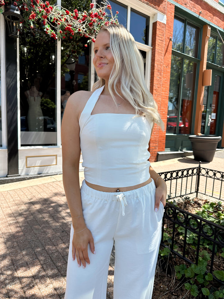 Woman wearing cream two piece pant set with square neck halter top. 