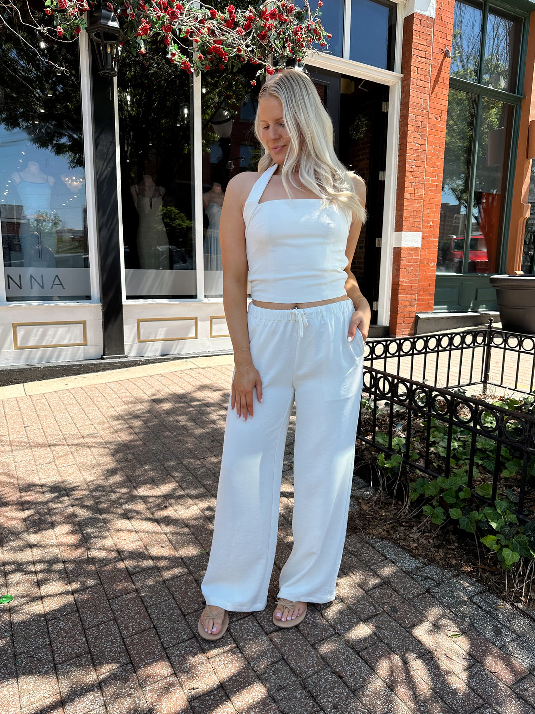 Woman wearing cream two piece pant set with square neck halter top. 