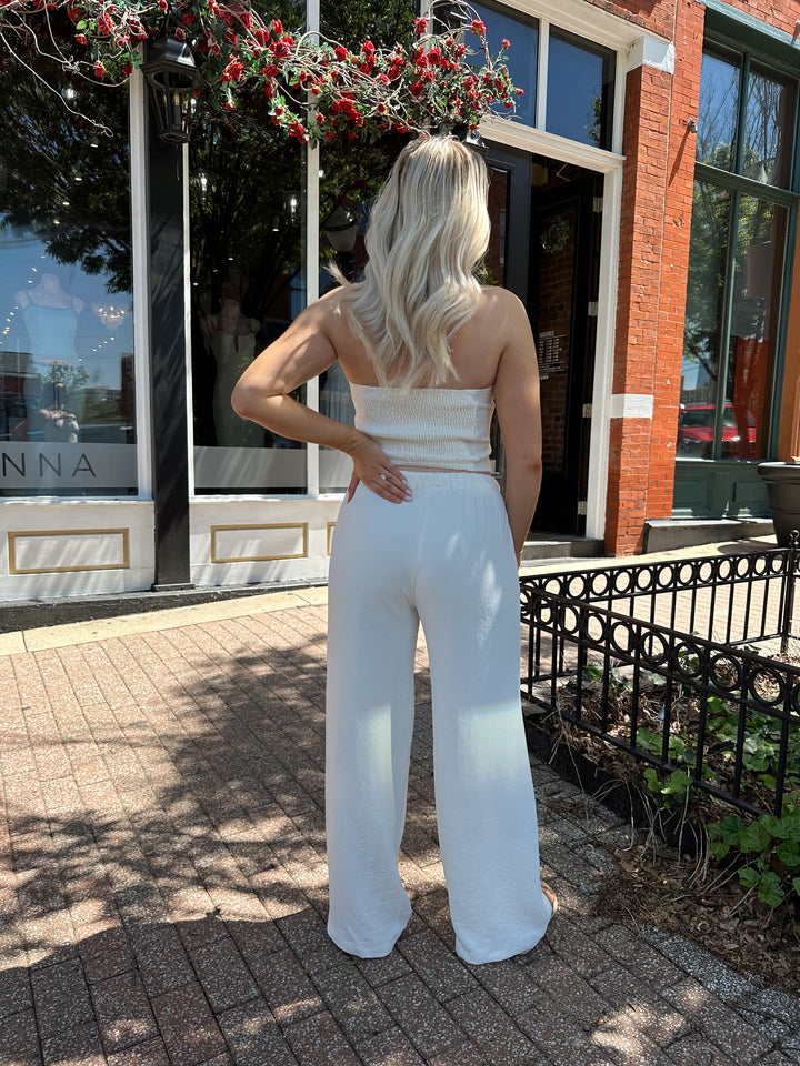 Woman wearing cream two piece pant set with square neck halter top. 