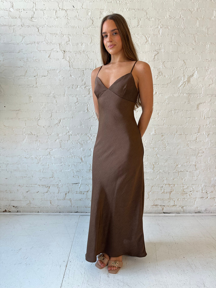 Woman wearing brown textured maxi dress with v-neckline and adjustable spaghetti straps. 