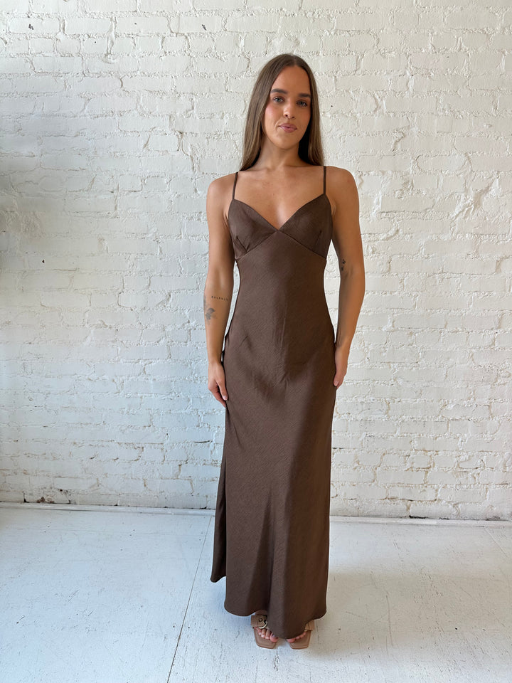 Woman wearing brown textured maxi dress with v-neckline and adjustable spaghetti straps. 