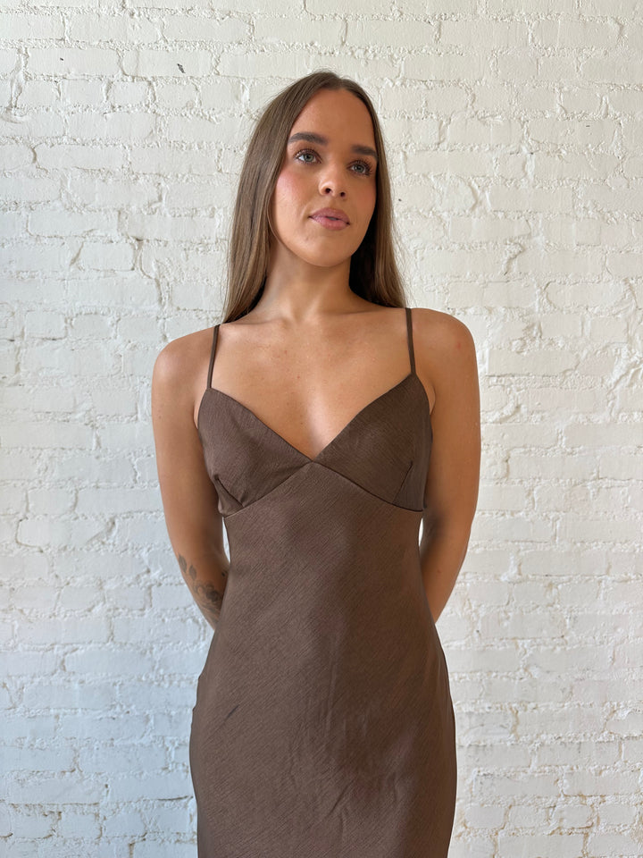 Woman wearing brown textured maxi dress with v-neckline and adjustable spaghetti straps. 