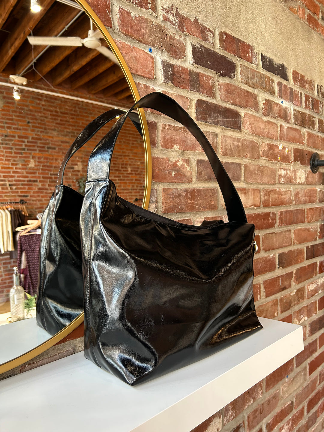 Black glossy oversized shoulder bag with metal detail.