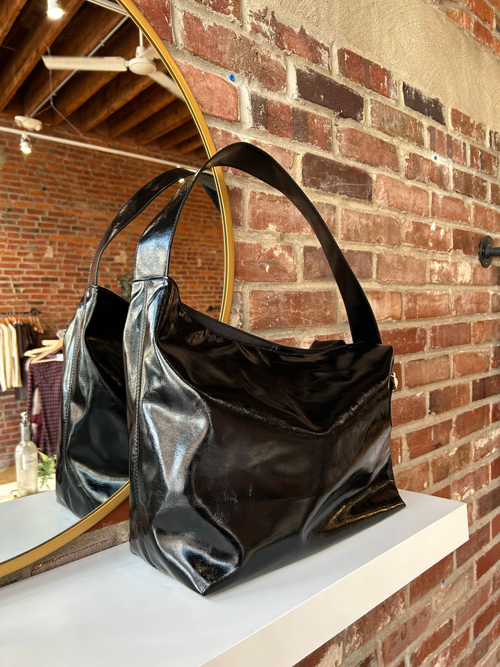 Black glossy oversized shoulder bag with metal detail.