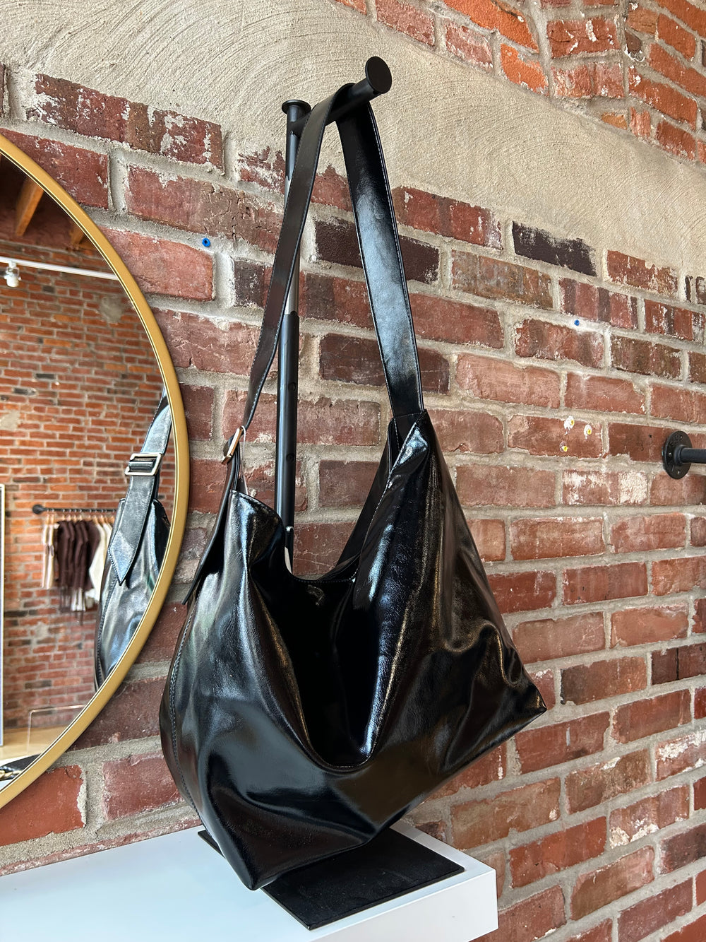 Black glossy oversized shoulder bag with metal detail.