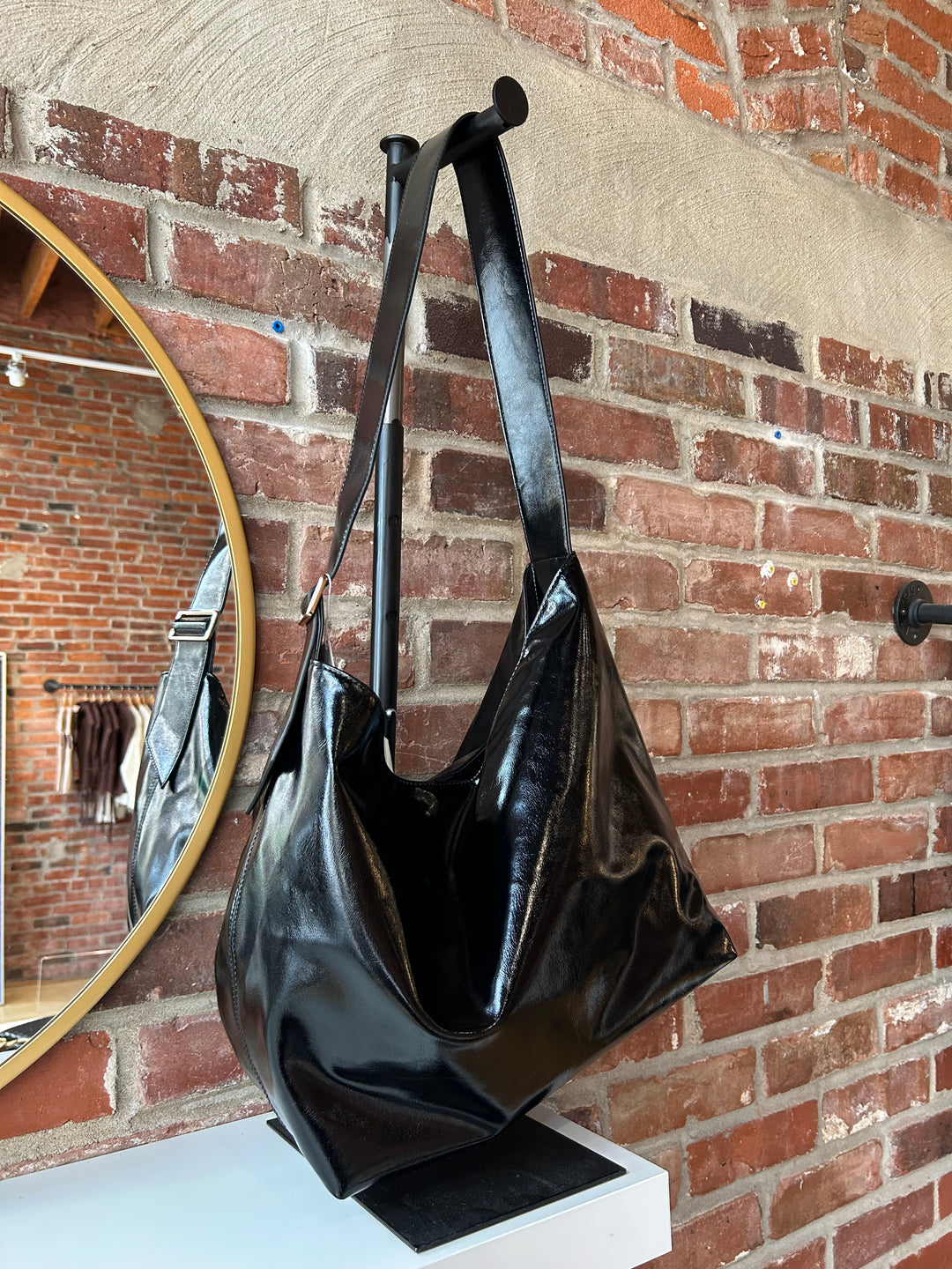 Black glossy oversized shoulder bag with metal detail.