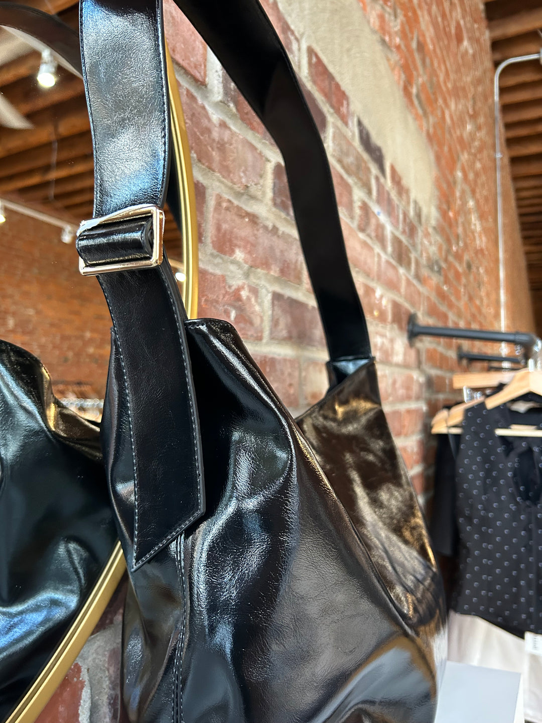 Black glossy oversized shoulder bag with metal detail.