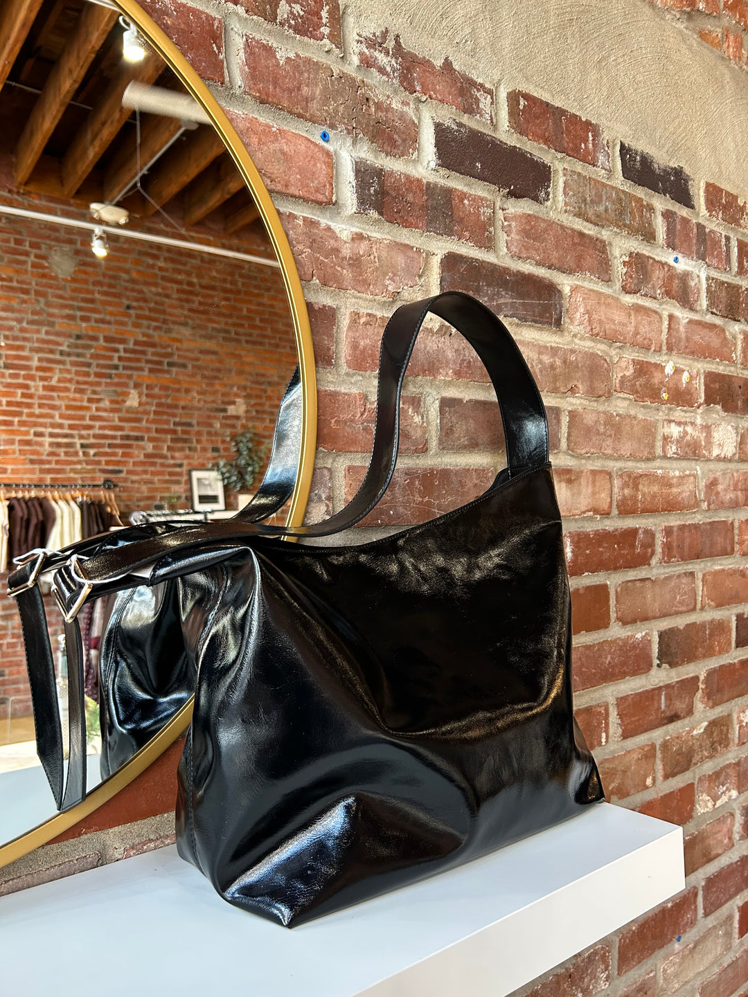 Black glossy oversized shoulder bag with metal detail.