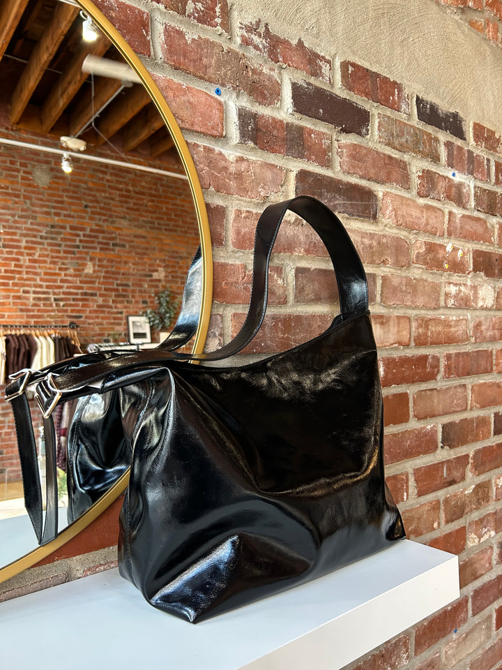 Black glossy oversized shoulder bag with metal detail.