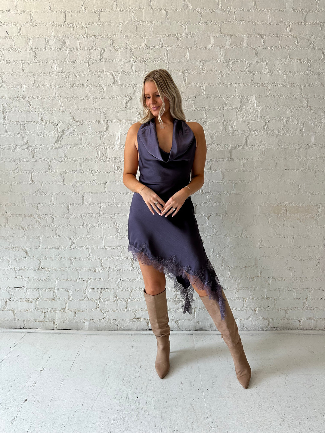 Woman wearing purple satin lace trim midi dress with self tie cowl halter neck. 
