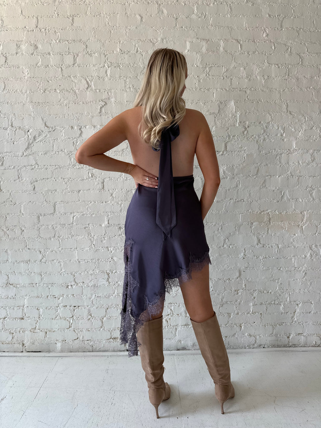 Woman wearing purple satin lace trim midi dress with self tie cowl halter neck. 