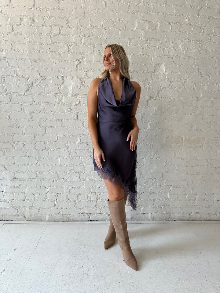 Woman wearing purple satin lace trim midi dress with self tie cowl halter neck. 
