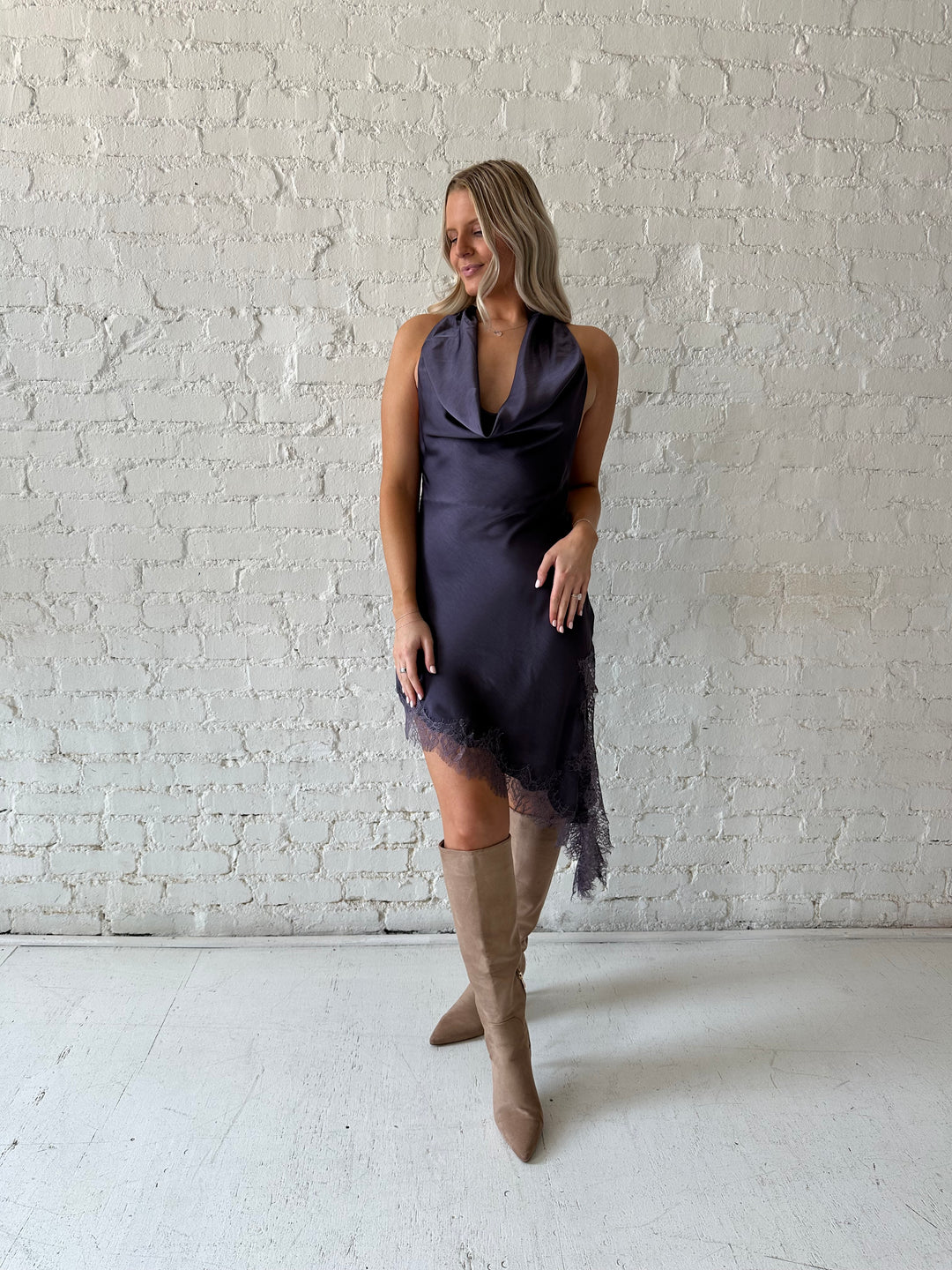 Woman wearing purple satin lace trim midi dress with self tie cowl halter neck. 