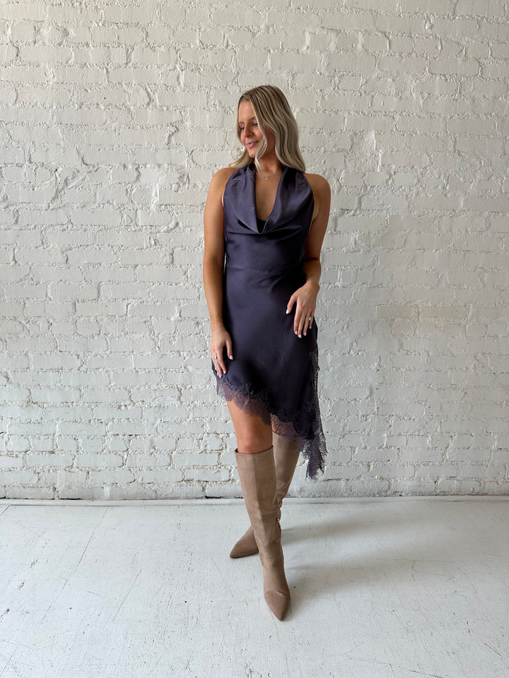 Woman wearing purple satin lace trim midi dress with self tie cowl halter neck. 