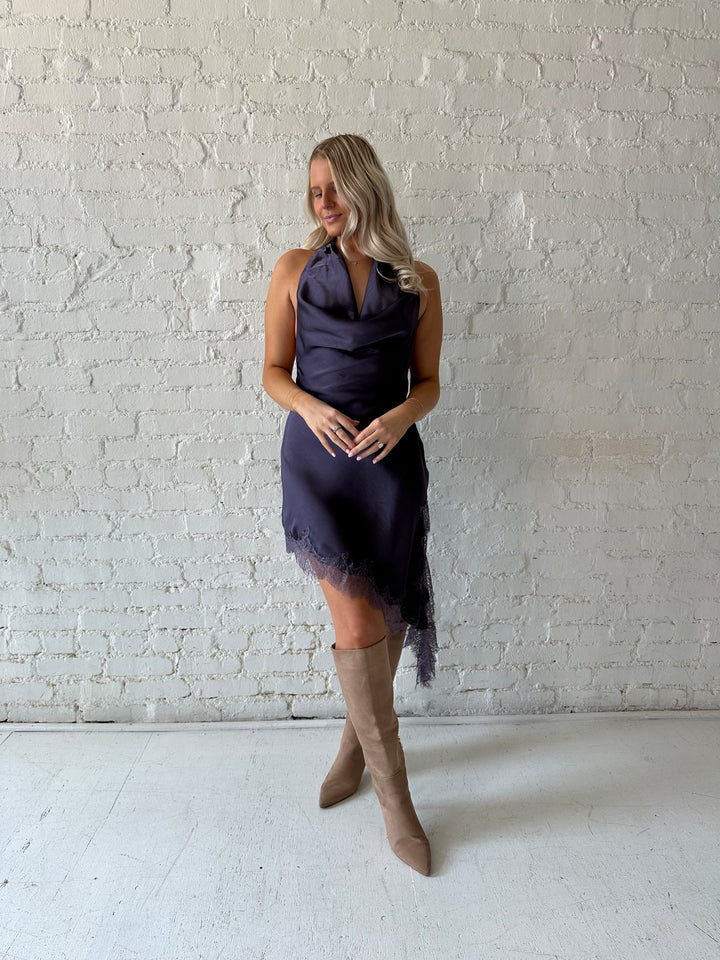 Woman wearing purple satin lace trim midi dress with self tie cowl halter neck. 